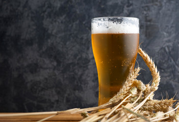 Misted glass of light beer on a wooden table and wheat