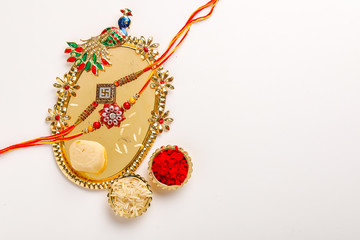 Indian festival Raksha Bandhan , Rakhi with rice grains, kumkum and sweets on plate 
