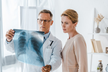 handsome doctor and attractive patient looking at x-ray in clinic