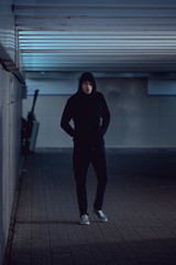 Fototapeta na wymiar thief in black hoodie walking in underpass