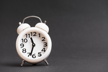 Vintage white alarm clock against black background