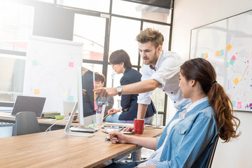 Obraz premium Group of four casual business meeting to discuss ideas and computer laptop on table in office.