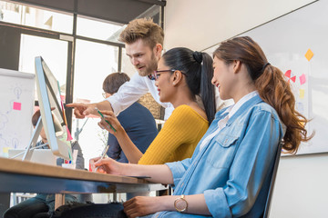 Group of five casual business meeting to discuss ideas and computer laptop on table in office.