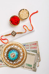 Indian festival Raksha Bandhan , Elegant Rakhi with rice , kumkum with Indian currency on white background