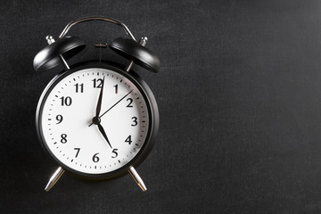 Alarm clock showing 5'o clock against black background
