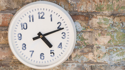 Round clock hanging on weathered brick wall