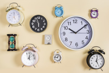 Different type of hour glass; clocks and alarm clocks on beige background