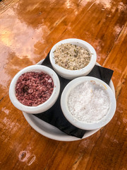 3 different types os salt on small white containers.