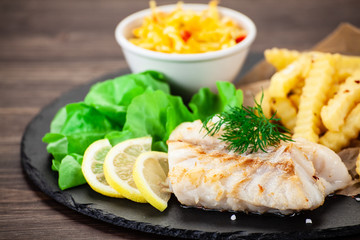 Fish dish - fried fish fillet with french fries and vegetables