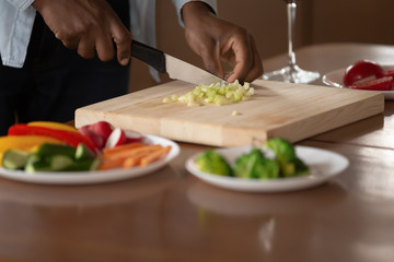 Obraz na płótnie Canvas African man chopping vegetables preparing dinner closeup hands