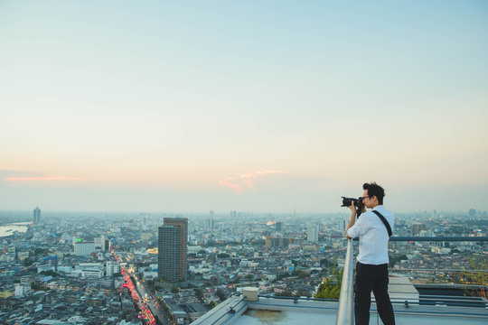 Photographer taking picture in city on top of building.