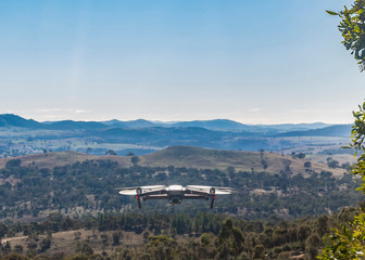 Fototapeta na wymiar A small modern unmanned aerial vehicle drone in flight showing landscape views and country scenery looking west of Canberra in the Australian Capital Territory