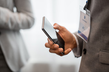 business, technology and people concept - close up of businessman with smartphone at conference
