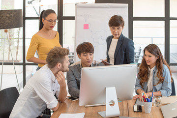 Obraz premium Group of five casual business meeting to discuss ideas and laptop on table in office.