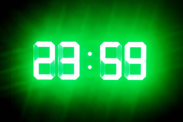 Green glowing digits in the dark show 23:59. Time is one minute to midnight.