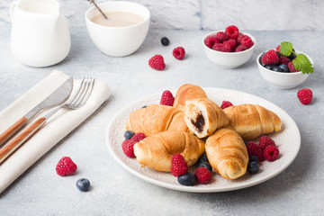 Croissants with fresh raspberries and blueberries on a dark concrete background. Copy space. concept of Breakfast coffee honey.
