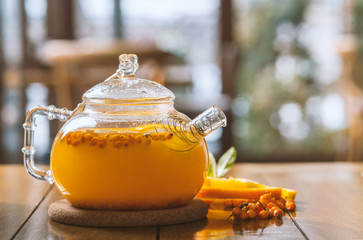 sea-buckthorn tea in a teapot on a wooden table