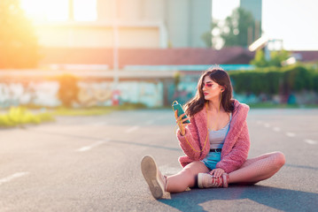 Young fashionable woman listening to music on headphones and smartphone