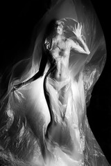 Slim girl dressed only in underwear emotionally posing, wrapped in fluttering in the wind and...