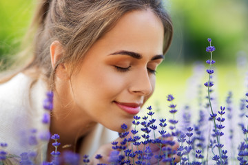 gardening and people concept - close up of happy young woman smelling lavender flowers at summer garden - obrazy, fototapety, plakaty