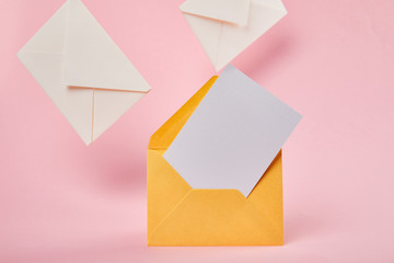 yellow bright envelope with blank white card near letters on pink background