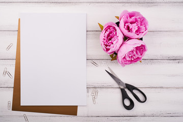 White paper on the wooden desk with flower and scissors