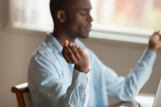 Serene african guy sitting indoors relaxing meditating
