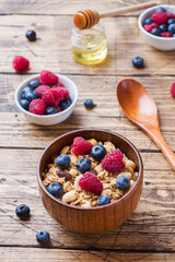 Healthy breakfast. Fresh granola, muesli with yogurt and berries on wooden background. Copy space.