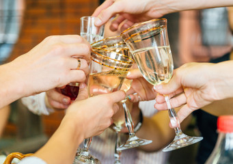 Friends clink glasses on a celebration. Holiday, birthday, new year soft focus background cheers