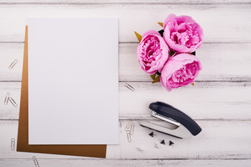 Blank paper on the wooden desk with flower and scissors