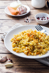 Vegetarian Oriental pilaf with rice and vegetables on a wooden table.