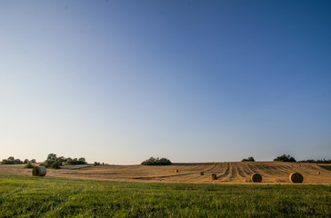 Landscape photo with blue sky, mowed field and hay bales