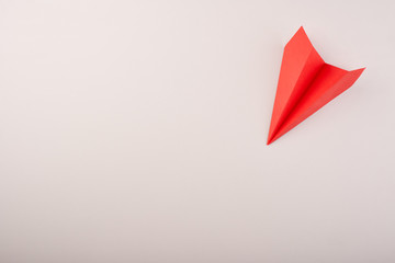 Origami red paper plane on the grey background