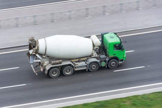 Truck with concrete mixer truck driving on the highway.
