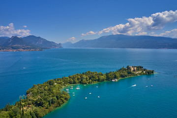 Obraz premium Unique view of the island of Garda. In the background is the Alps. Resort place on Lake Garda north of Italy. Aerial photography.