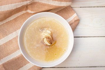 Bowl of pork bone soup with herbs on wood table