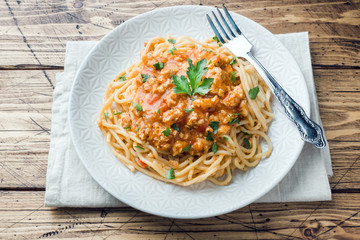 Spaghetti pasta Bolognese on white plate, wooden table