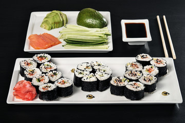 Set of rolls with red fish and ginger. Table setting. Black background.