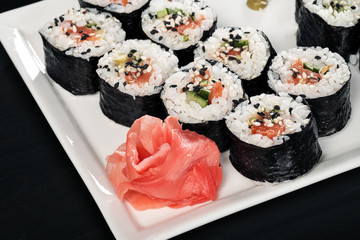Set of rolls with red fish and ginger. Table setting. Black background.