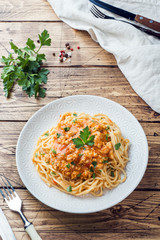 Spaghetti pasta Bolognese on white plate, wooden table
