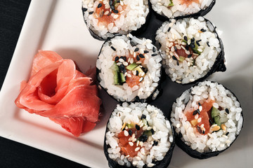 Set of rolls with red fish and ginger. Table setting. Black background.