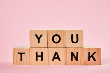 wooden blocks with thank you words on pink background with copy space