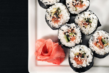 Set of rolls with red fish and ginger. Table setting. Black background.