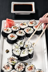 Set of rolls with red fish and ginger. Table setting. Black background. Ingredients for cooking Japanese cuisine.