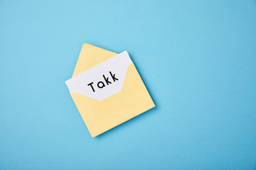 yellow envelope and white card with takk word on blue background