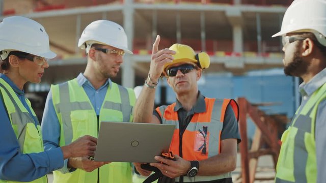 
Diverse Team of Specialists Use Laptop Computer on Construction Site. Real Estate Building Project with Civil Engineer, Architectural Investor, Businesswoman and Worker Discussing Plan Details