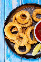 Onion rings with sauce on wooden table