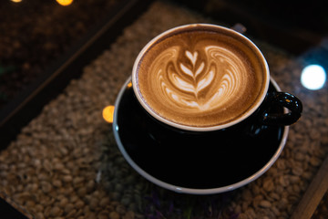 Latte art coffee in black cup on  table, Dark tone