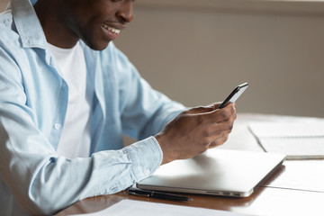 Cropped closeup image african guy sit at table using smartphone