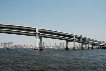 A large modern bridge crosses one of Tokyo's waterways